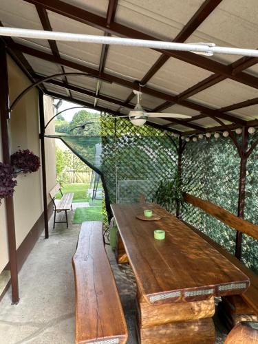 uma mesa de madeira e bancos sob uma pérgola em Apartma Zeleni Raj em Ptuj