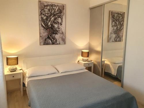 ein Schlafzimmer mit einem Bett, zwei Lampen und einem Spiegel in der Unterkunft Apartman Rabatin in Sveti Filip i Jakov