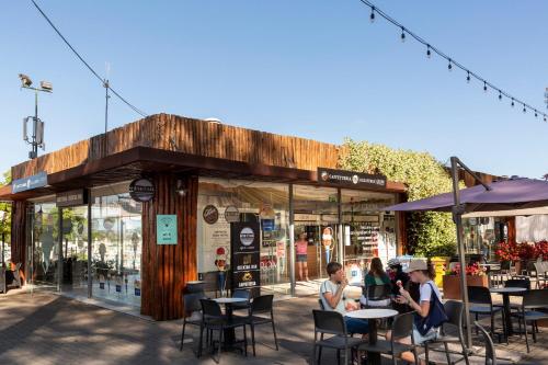 un grupo de personas sentadas en las mesas fuera de un restaurante en Fabulous village, en Casal Palocco