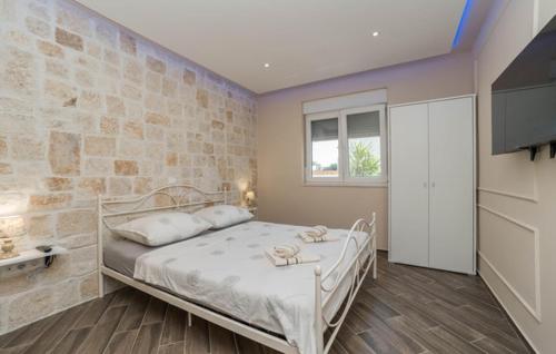 a bedroom with a white bed and a stone wall at Villa Strkalj Bibinje in Bibinje