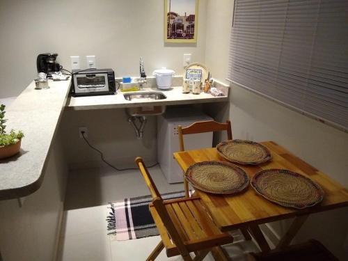 a small kitchen with a wooden table and a sink at Suites em Jabaquara, Paraty in Paraty