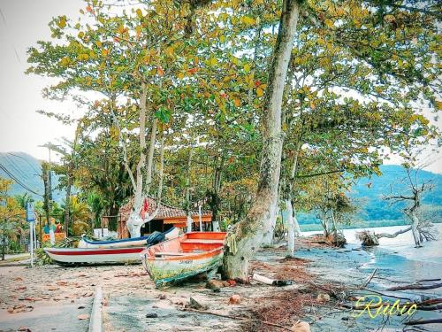 a painting of two boats parked next to trees at Suites em Jabaquara, Paraty in Paraty