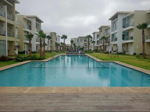 una gran piscina frente a algunos edificios de apartamentos en Casabay appartement pied dans l'eau 87 m2 en Sidi Rahal