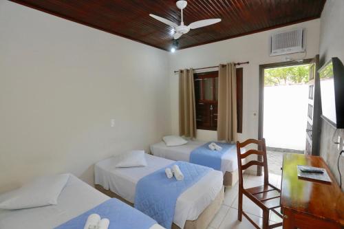 a room with two beds and a chair in it at Pousada Albamar Guarujá in Guarujá