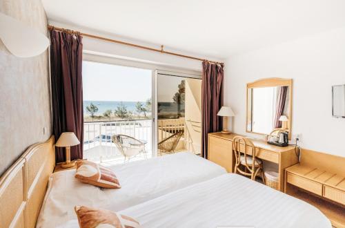 a hotel room with a bed and a balcony at Hôtel Édenia - Spa Estime&Sens in Carnac