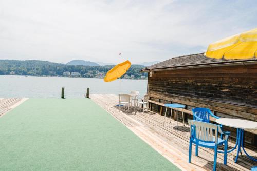 a dock with a table and chairs and an umbrella at Gästehaus Frank in Velden am Wörthersee