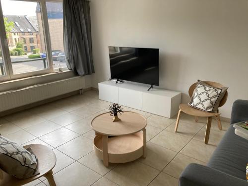 a living room with a tv and a couch and a table at feelaathome in Louvain-la-Neuve
