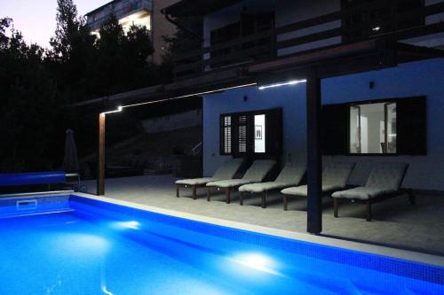 a swimming pool with chairs next to a building at night at Villa Hedonic in Ulcinj