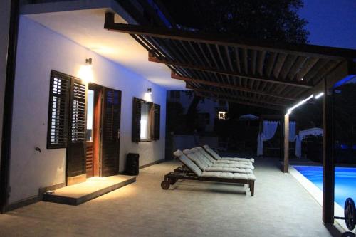a patio with a couch and a pool at night at Villa Hedonic in Ulcinj