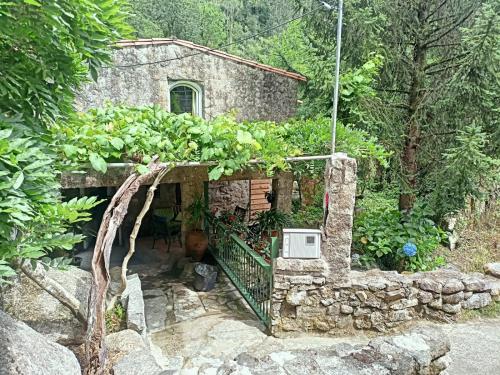 uma pequena casa de pedra com um jardim em frente em Molino cascada de caldas de reyes em Caldas de Reis