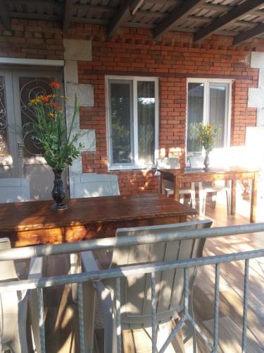 een patio met houten tafels en stoelen en een bakstenen muur bij Guest House Darejani in Koetaisi