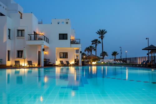 a swimming pool in front of a building at night at Jacob Sea Life Nahariya in Nahariyya