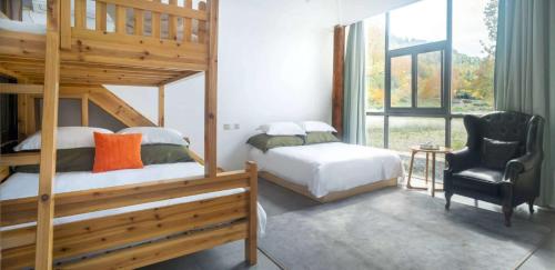 a bedroom with two bunk beds and a chair at Alina Garden Boutique Resort Huangshan Hongcun in Huangshan Scenic Area