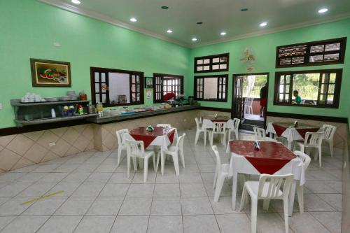 a restaurant with tables and white chairs and green walls at Pousada Albamar Guarujá in Guarujá