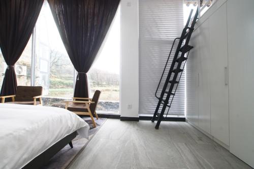 a bedroom with a bed and a ladder next to a window at Alina Garden Boutique Resort Huangshan Hongcun in Huangshan Scenic Area