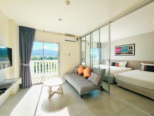 a hotel room with a couch and a bed at Recenta Suite Phuket Suanluang in Phuket Town