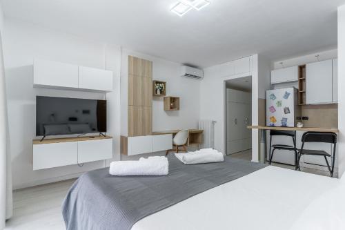 a white bedroom with a large bed and a television at Santa Giulia Suite in Milan