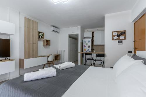 a white bedroom with a large bed and a kitchen at Santa Giulia Suite in Milan