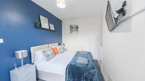 a bedroom with a bed with a blue wall at Spacious 2 Bedroom Apartment in Barrow in Furness
