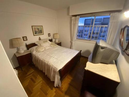 ein Schlafzimmer mit einem Bett, einem Fernseher und einem Fenster in der Unterkunft 4 ambientes vista al mar cochera seguridad 24hs in Mar del Plata