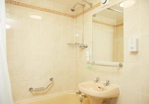 y baño con lavabo, aseo y espejo. en The Broughton Hotel by Greene King Inns en Milton Keynes