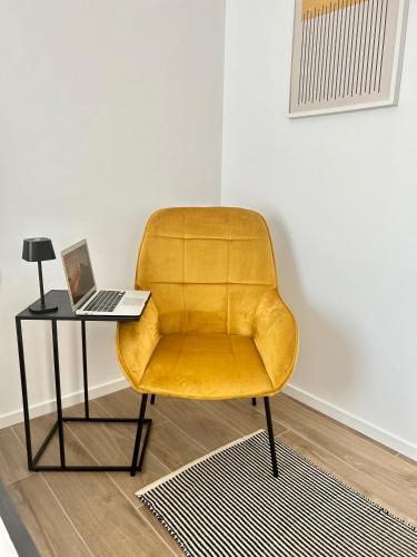 a yellow chair sitting next to a table with a laptop at AURUS in Korčula