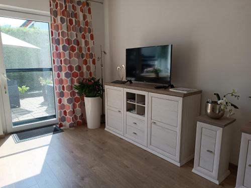 a living room with a flat screen tv on a cabinet at Ferienwohnung Sonnenblick und Relax in Nieder-Röhre