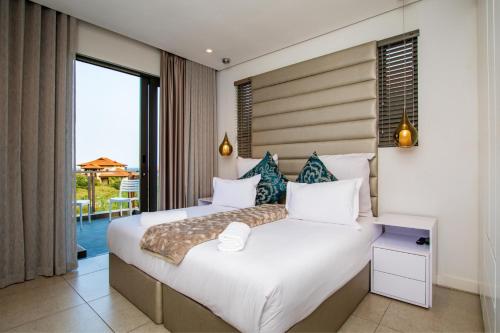 a bedroom with a large bed and a balcony at Oceans Edge 5, Zimbali Estate in Ballito