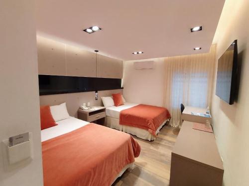 Habitación de hotel con 2 camas y TV de pantalla plana. en Global Hotel en Centenario
