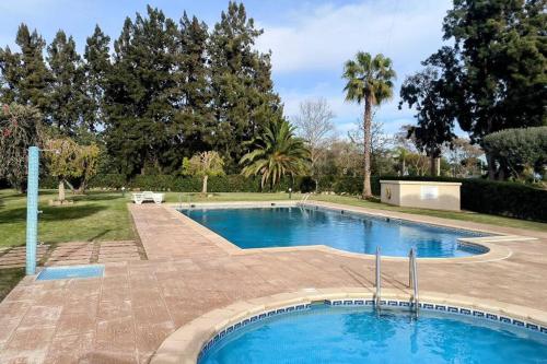 een groot zwembad in een tuin met bomen bij Casa das Mélias in Quarteira