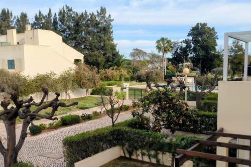 uma vista para um jardim com um edifício e árvores em Casa das Mélias em Quarteira