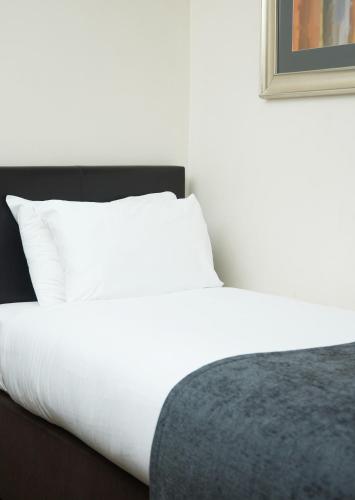 a bedroom with a white bed and a white pillow at The Broughton Hotel by Greene King Inns in Milton Keynes