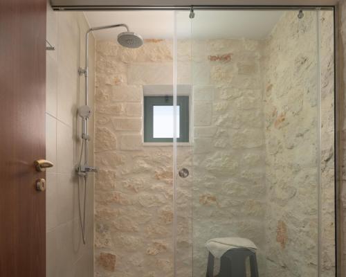 a glass shower with a stool in a bathroom at Mouria Country House in Gállos