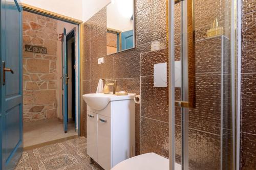 e bagno con servizi igienici, lavandino e doccia. di Apartments Villa Domus Marini a Hvar