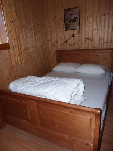 un lit dans une chambre avec un mur en bois dans l'établissement Two Bedroom Apartement Belle Vue, à La Chapelle-dʼAbondance