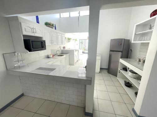 阿拉胡埃拉的住宿－3 Min from SJO airport Kaeli，厨房配有白色橱柜和冰箱。