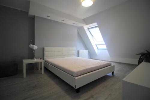 ein weißes Schlafzimmer mit einem Bett und einem Fenster in der Unterkunft Bulwar Apartament in Głogów