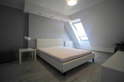 a white bedroom with a bed and a window at Bulwar Apartament in Głogów