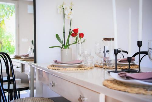 - une table à manger avec des assiettes, des verres et des fleurs dans l'établissement Venez Chez Vous - Aux Premières Loges Appartement Pieds dans l'eau, à Sévrier