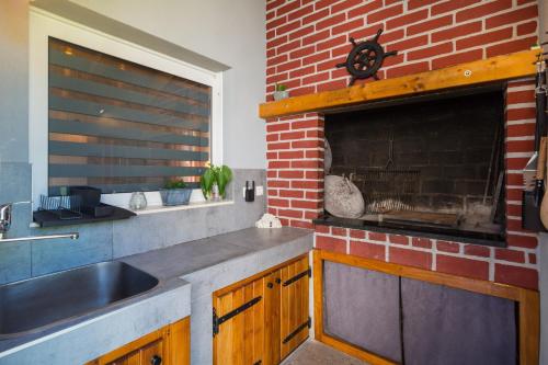 Studio apartman Mediteran في مارينا: مطبخ مع حوض وجدار من الطوب