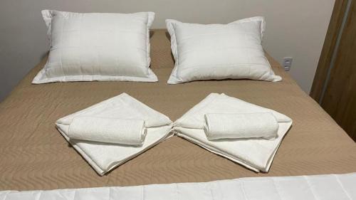 a bed with white pillows and towels on it at Apartamento Studio Centro Poços de Caldas in Poços de Caldas