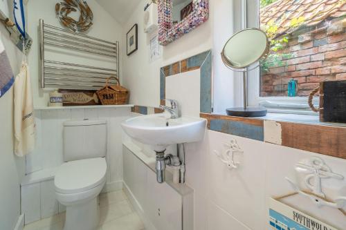 ein Badezimmer mit einem Waschbecken, einem WC und einem Spiegel in der Unterkunft Alec Hill's Bakehouse in Wangford