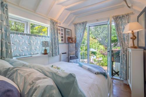 a bedroom with a bed with blue curtains and a window at Alec Hill's Bakehouse in Wangford