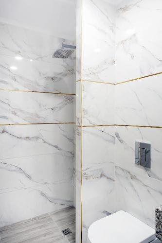 a bathroom with white marble walls and a toilet at Okean Apartments in Ierissos
