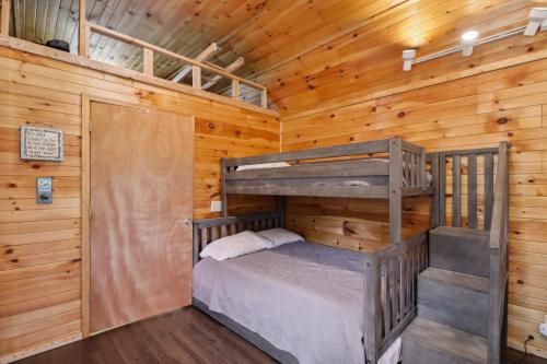 a bedroom with two bunk beds in a wooden cabin at Higden Hideaway with Fire Pit Near Greers Ferry Lake in Fairfield Bay