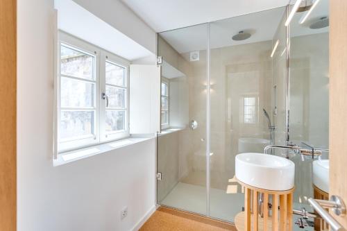 a bathroom with a glass shower and a sink at Miragaia Apartments by DA'HOME in Porto