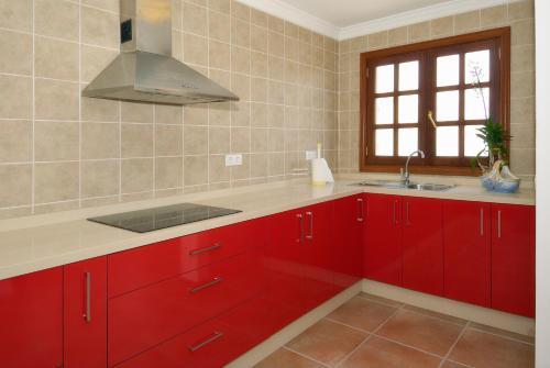 una cocina con armarios rojos y fregadero en Apartment Limonade Deluxe Main Center Playa Blanca By PVL en Playa Blanca