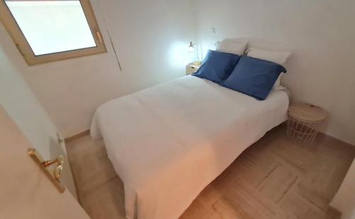 um quarto com uma cama branca e almofadas azuis em Cannes Marina vue sur le port em Mandelieu-la-Napoule