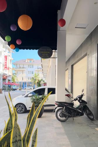 a motorcycle parked outside of a building with a car at Tuần Châu - Phương Đông Motel Hạ Long in Ha Long