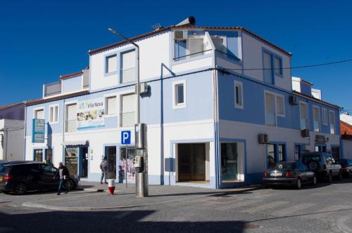 a white building with a parking lot in front of it at Apartamentos Vila Nova in Vila Nova de Milfontes